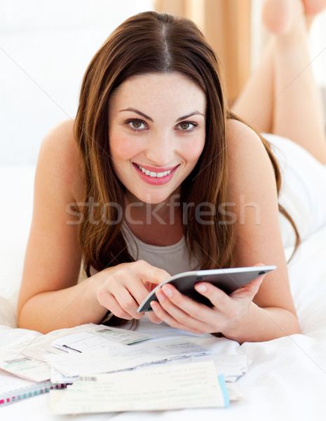 Young woman doing her accounts lying on bed Stock photo © wavebreak_media