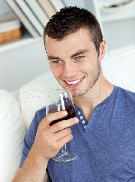 Animated young man drinking wine sitting on the sofa in the living-room Stock photo © wavebreak_media