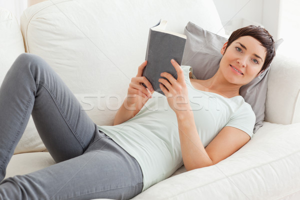 Beautiful brunette holding a book while looking at the camera Stock photo © wavebreak_media