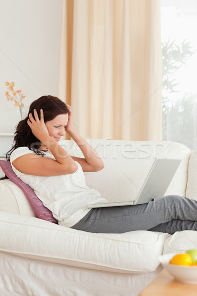 Frustrated woman with a notebook in her livingroom Stock photo © wavebreak_media