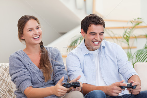 Stock photo: Smiling couple playing video games in their living room