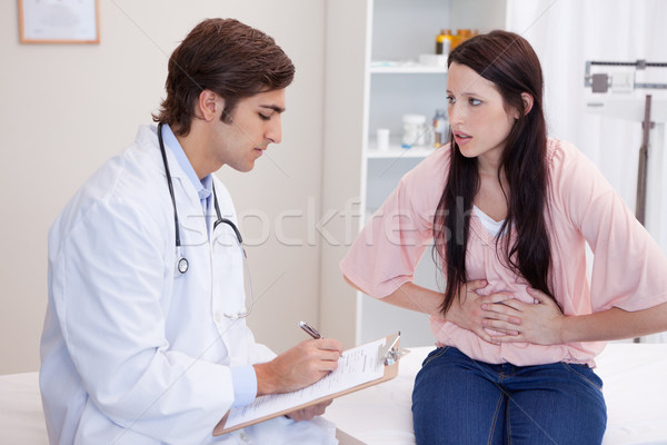 Young male doctor writing down female patients symptoms Stock photo © wavebreak_media