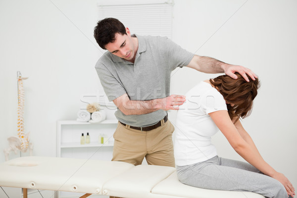 Physiotherapist looking at the spinal column of a woman in a medical room Stock photo © wavebreak_media