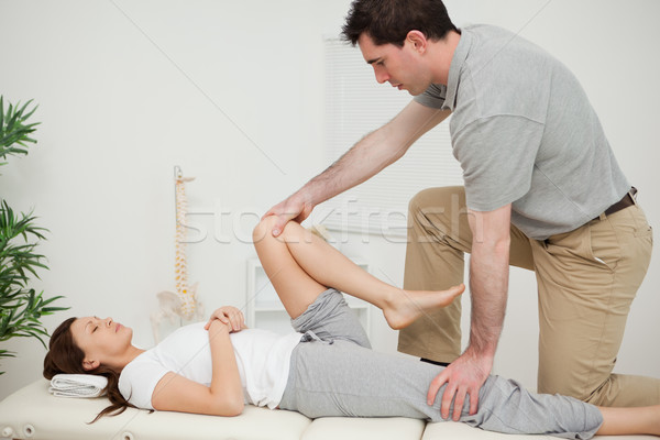 Serious doctor stretching the leg of a woman in a room Stock photo © wavebreak_media