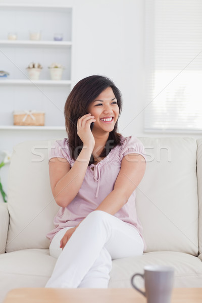 Happy woman phoning while sitting on a couch in a living room Stock photo © wavebreak_media