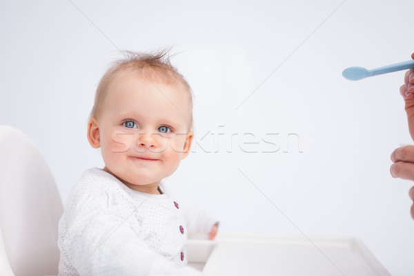 Smiling baby looking at the camera while being fed against a grey background Stock photo © wavebreak_media