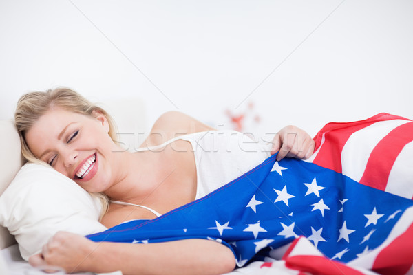 Laughing blonde woman with a US flag in her bed Stock photo © wavebreak_media