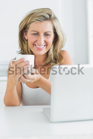 Mosolygó nő tart bögre néz laptop számítógép Stock fotó © wavebreak_media