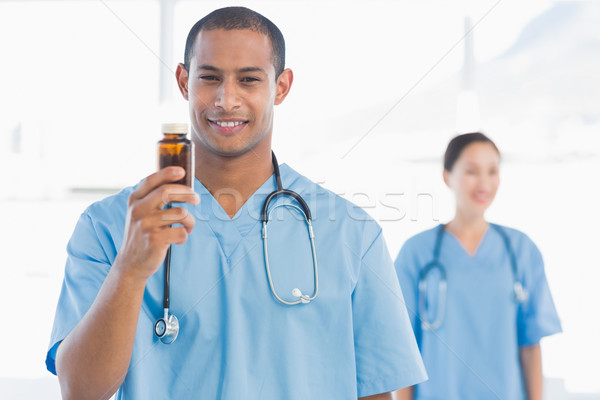 Smiling doctor holding a bottle of pills with colleague Stock photo © wavebreak_media