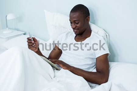 Boldog férfi ül ágy okostelefon otthon Stock fotó © wavebreak_media