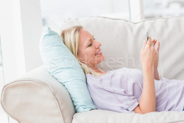 Woman listening music while lying on sofa Stock photo © wavebreak_media