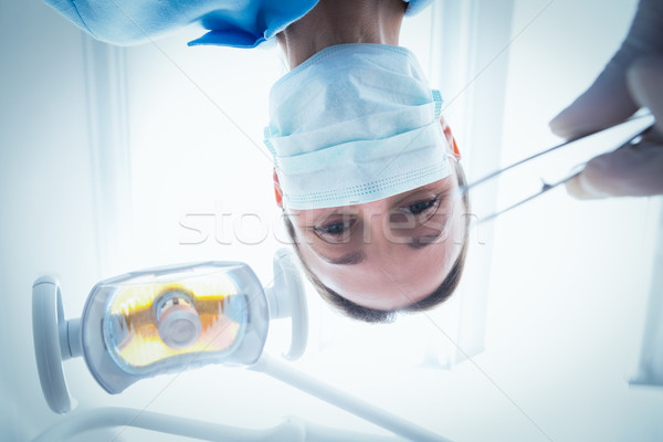 Female dentist in surgical mask holding dental tool Stock photo © wavebreak_media