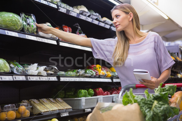 Smiling woman reading on his notepad in aisle  Stock photo © wavebreak_media