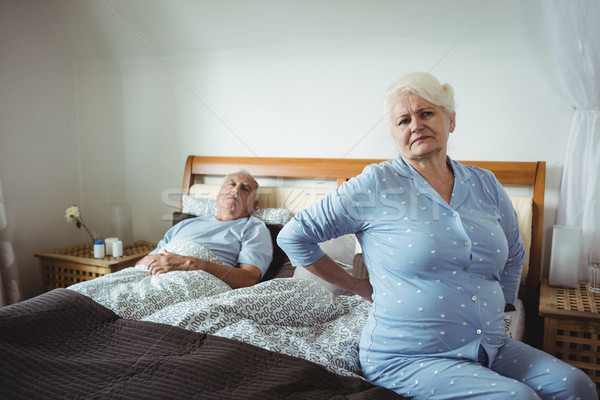 Stock photo: Senior woman suffering from backache sitting on bed