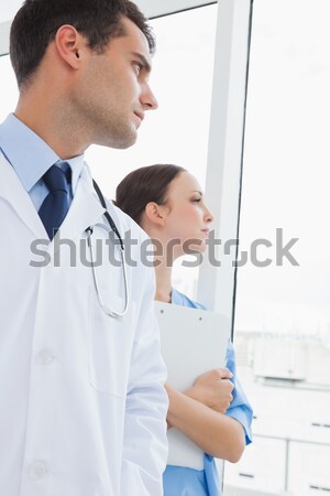 Doctor looking at report while patient sleeping on bed Stock photo © wavebreak_media