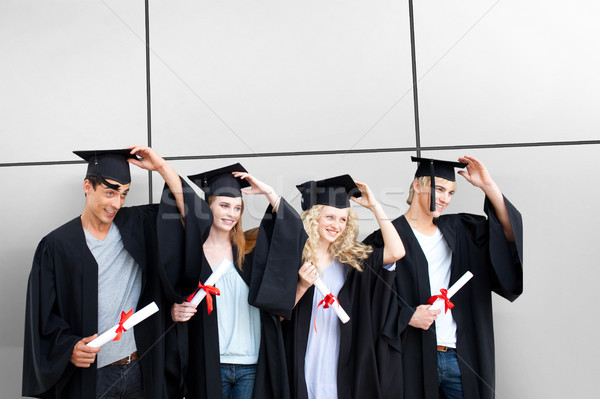 Group of teenagers celebrating after Graduation against white tiling Stock photo © wavebreak_media