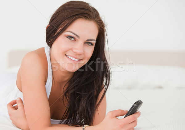 Stock photo: Beautiful young woman texting in her bedroom