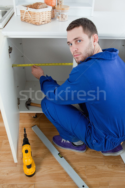 Portrait of a young repair man measuring something in a kitchen Stock photo © wavebreak_media