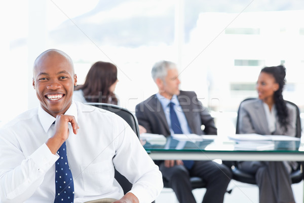 Stock photo: Executive laughing while looking at the camera with his team in the background