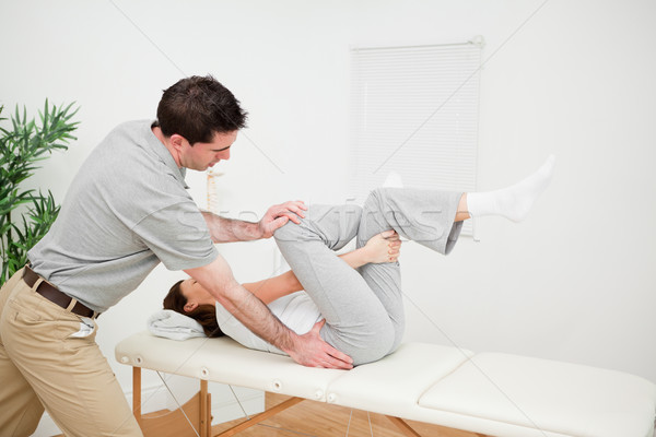 Stock photo: Physiotherapist pushing the leg of a woman on the side in a medical room