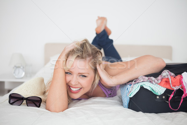 Laughing young woman lying next to her full suitcase on her bed Stock photo © wavebreak_media