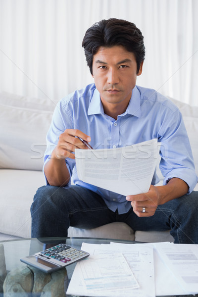 Stock photo: Man sitting on couch working out his finances