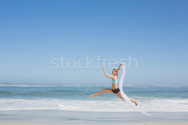 Fit woman jumping gracefully on the beach with scarf Stock photo © wavebreak_media