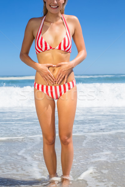 Smiling fit woman in bikini on the beach touching her stomach Stock photo © wavebreak_media