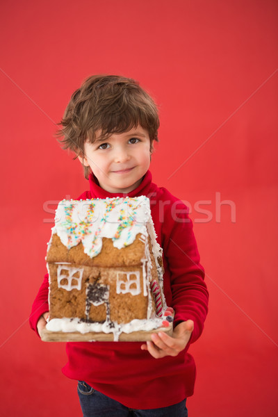 Festive little boy holding gingerbread house Stock photo © wavebreak_media