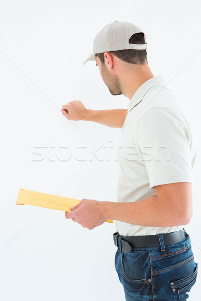 Delivery man with envelop knocking on white background Stock photo © wavebreak_media