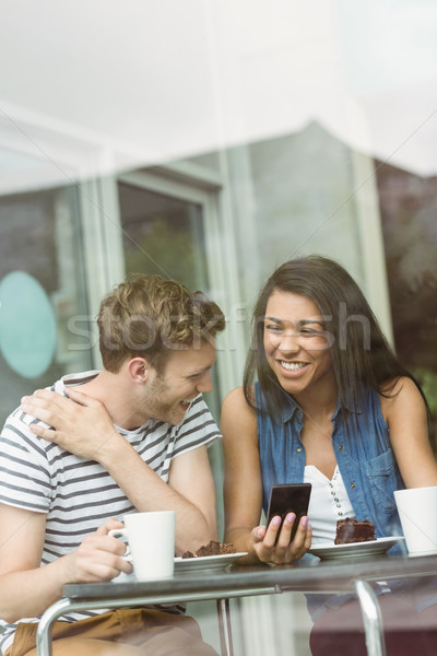 Stock photo: Smiling friends with chocolate cake using smartphone