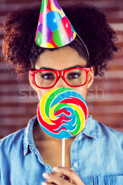 Portrait of a hipster with a party hat holding a lollipop Stock photo © wavebreak_media