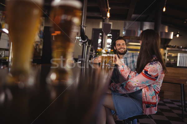 Happy couple interacting while having beer at counter Stock photo © wavebreak_media