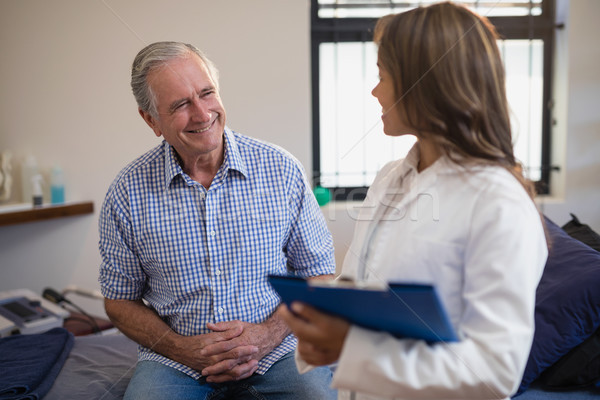 Smiling senior male patient looking at female therapist with file Stock photo © wavebreak_media
