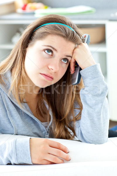 Bored young woman holdinga  remote sitting in the kitchen Stock photo © wavebreak_media