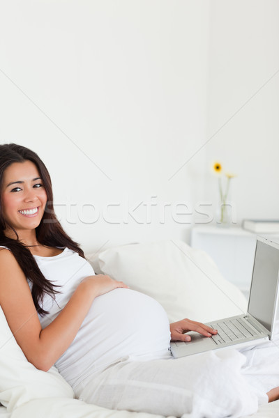 Cute pregnant woman relaxing with her laptop while lying on a bed at home Stock photo © wavebreak_media