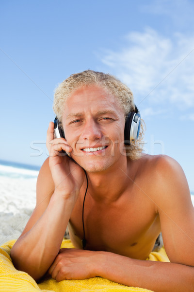 Young blonde man attentively listening to music with his headset Stock photo © wavebreak_media