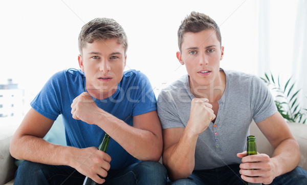 Two guys with beers in their hands look into the camera and celebrate by shaking their fist slightly Stock photo © wavebreak_media