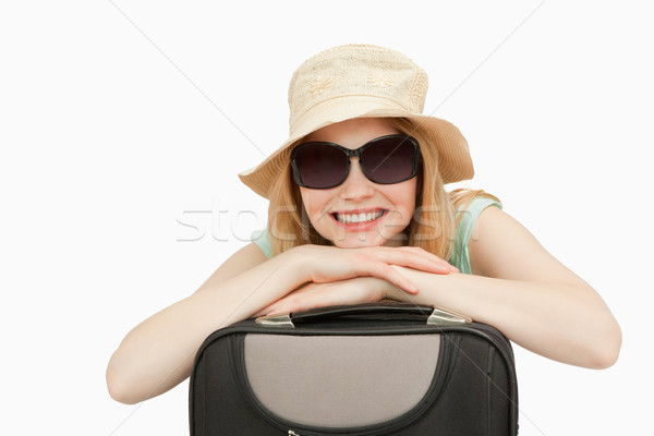 Stock photo: Cheerful woman leaning on a suitcase against white background