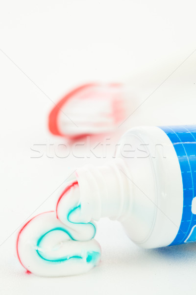 Blue tube of toothpaste next to a toothbrush against white background Stock photo © wavebreak_media