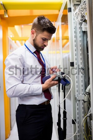 Man checking tablet pc as he is plugging cables into server in data center Stock photo © wavebreak_media