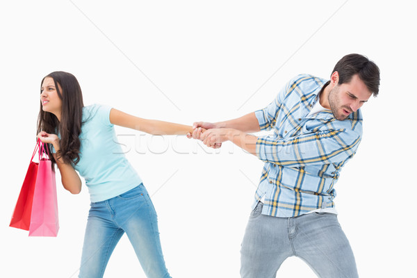 Attractive young man pulling his shopaholic girlfriend Stock photo © wavebreak_media