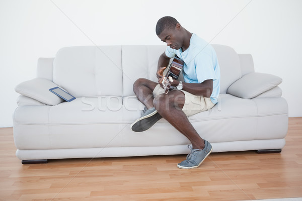 Casual homem sessão sofá jogar guitarra Foto stock © wavebreak_media