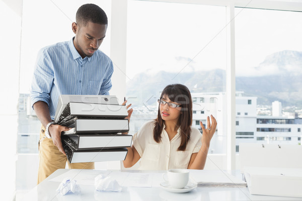 Man giving pile of files to his exasperated colleague Stock photo © wavebreak_media