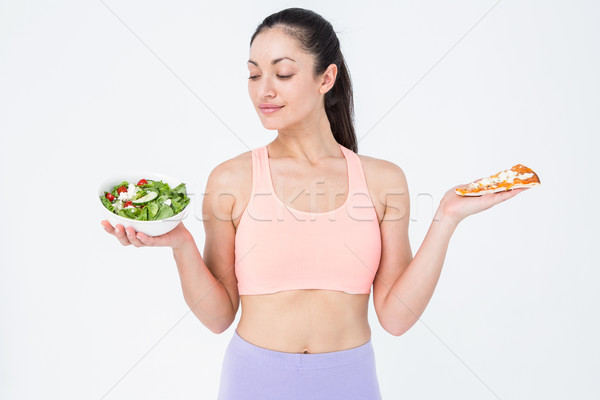 Smiling brunette looking at salad while holding pizza Stock photo © wavebreak_media