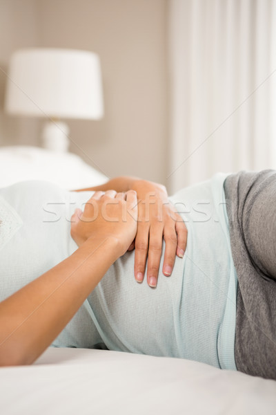 Femeie mâini stomac pat acasă Imagine de stoc © wavebreak_media