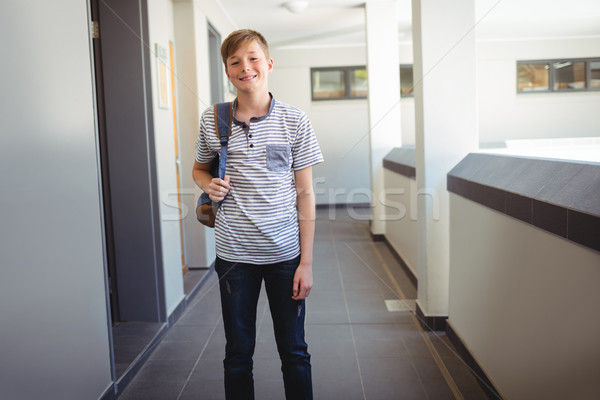Smiling schoolboy standing with schoolbag in corridor at school Stock photo © wavebreak_media