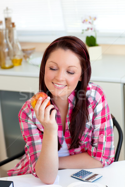 Smiling woman holding an apple sitting in the kitchen Stock photo © wavebreak_media
