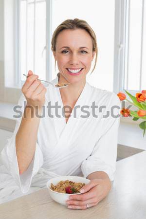 Stock photo: Smiling woman relaxing on her laptop while drinking a glass of milk in her kitchen