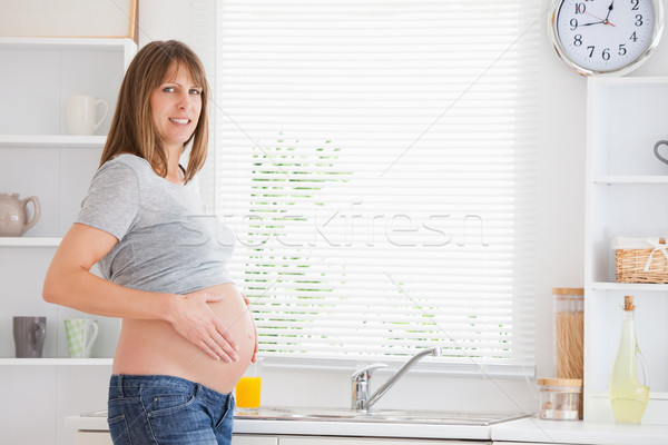Beautiful pregnant woman caressing her belly while standing in a kitchen Stock photo © wavebreak_media